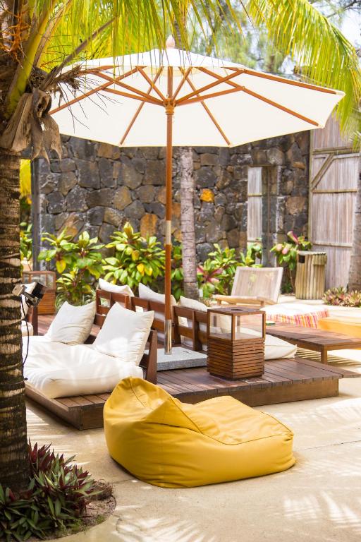 Atpūtas zona ar spilveniem, dīvāniem un sauļošanās nojumi, ieskauta zaļojošiem augiem un akmens sienām. Ideāla vieta relaksācijai un atpūtai.