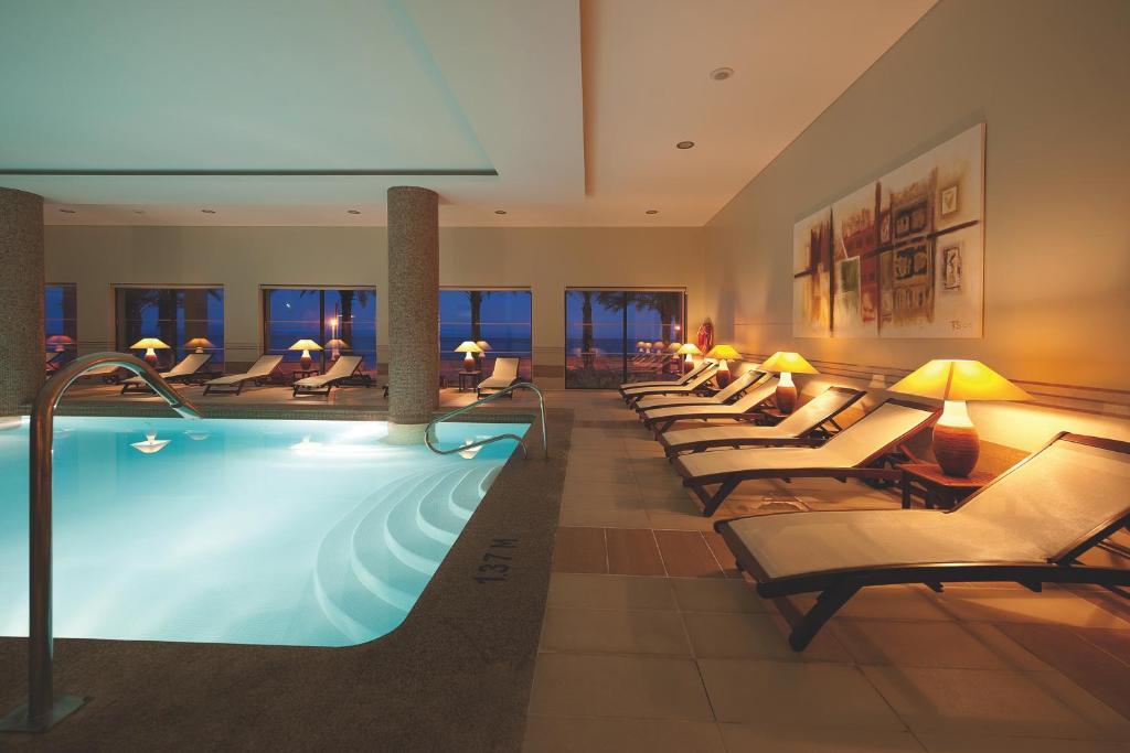 Relaksējoša spa telpa ar iekšējo baseinu, sauļošanās krēsliem un mīkstu apgaismojumu. Logi piedāvā skatu uz jūru, radot mierīgu atmosfēru.