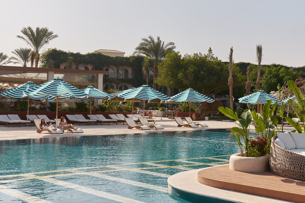 Desert Rose Resort baseins ar sauļošanās krēsliem un saulessargiem.