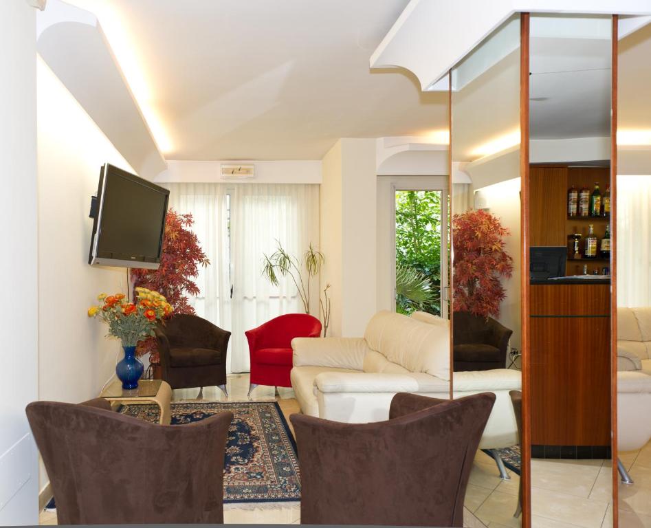 Mūsdienīgs viesistabas interjers ar gaismu, dabu un ērtu mēbelējumu. Sarkanā un brūnā krāsā veidotas krēsli, balta dīvāna un televizora elements papildina telpas estētiku.