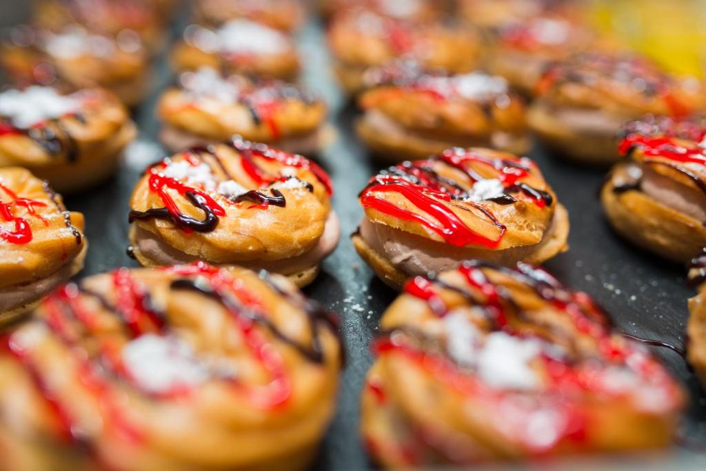 Saldiem deserti ar šokolādes un ogu mērci, izkārtoti rindā uz trauka. Izskatās mutē šķidri un pievilcīgi.