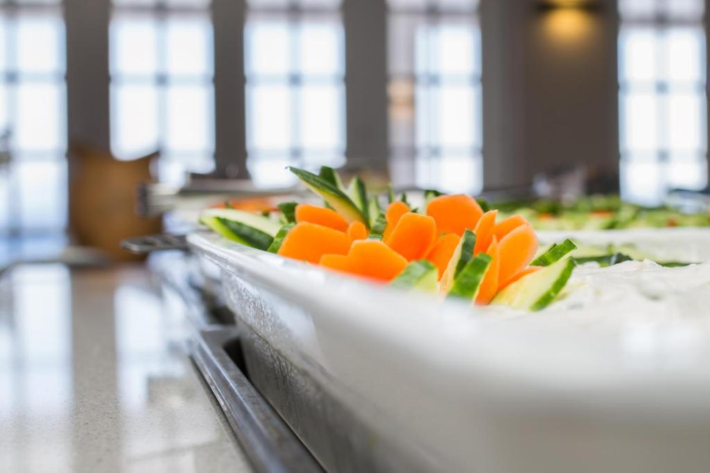 Svaigu dārzeņu plate ar burkāniem un gurķiem, kas pasniegta gaišā interjerā. Ideāla izvēle veselīgām maltītēm.