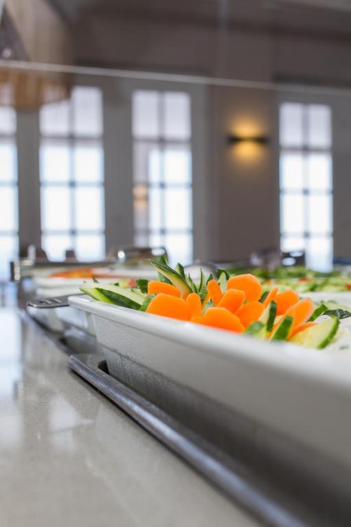 Svaigi griezti dārzeņi uz galda, ar burkāniem un gurķiem, kas izkārtoti gaumīgi, radot pievilcīgu skatu restorānā.