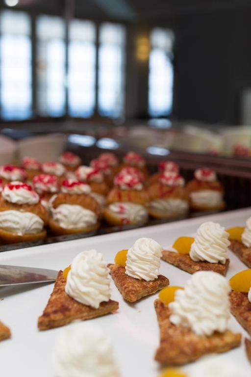 Saldumu šķīvis ar krēmveida desertiem, tostarp kārtainā mīklā un biskvīta kūciņām ar krējumu.
