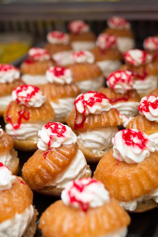 Saldējuma kūkas ar krēmīgu pildījumu un sarkano ogu mērci, dekorētas ar putotu krējumu, kas veido garšīgu desertu.