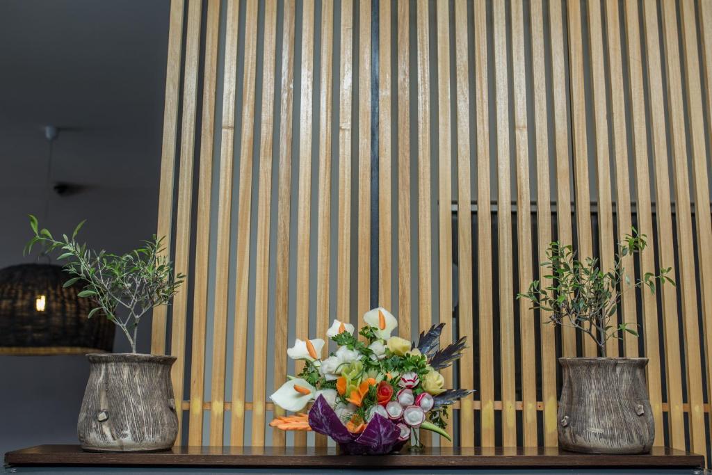 Ziedu kompozīcija elegantā interjerā ar koka ribām un divām podiņiem no māla.