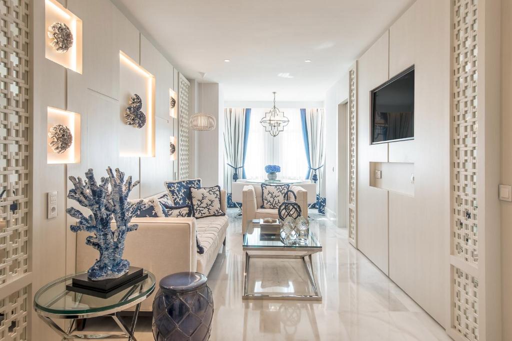 Mūsdienīgs un elegants viesistabas interjers ar gaišām krāsām, dekoratīvām sienām un stilīgām mēbelēm. Uz galda atrodas dekoratīvi priekšmeti, kas piešķir telpai pievilcīgu atmosfēru.