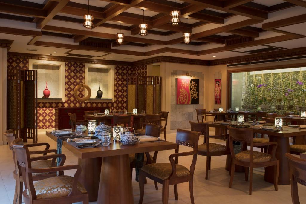 Mūsdienīgs restorāns ar elegantām koka mēbelēm, dekoratīvām sienām un intīmu apgaismojumu, radot patīkamu atmosfēru ēdienreizei. Galdi ir saklāti ar galda piederumiem un dekoratīvām svečturiem.