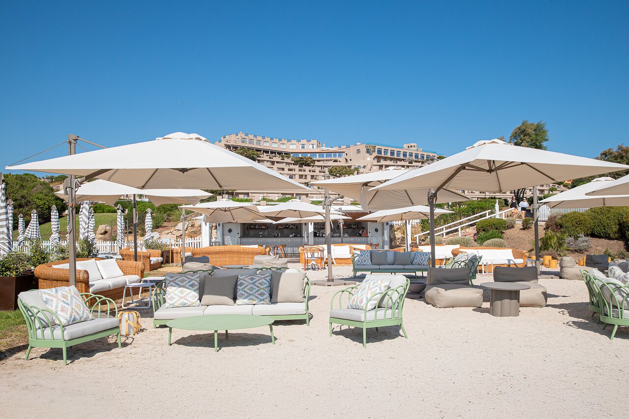 Atpūtas zona pludmalē Mangia's Sardinia Resort ar sauļošanās krēsliem un saulessargiem.