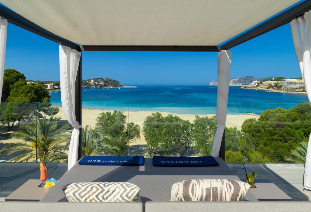 Skaists skats uz pludmali no greznas atpūtas zonas, ar palmām un zilām jūras ūdenīm fonā. Uz galda atrodas dzērieni un uzkodas, kas rada relaksējošu atmosfēru.