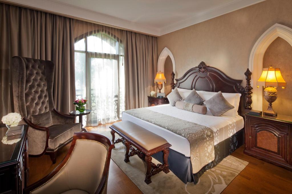 Elegantā viesnīcas numura interjers ar greznu gultu, klasiskām mēbelēm un dabiskiem apgaismojuma avotiem. Logi piedāvā skatu uz dārzu un gaismu telpā.