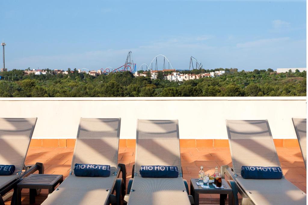 Sauļošanās krēsli uz viesnīcas terases ar skatu uz tuvumā esošajiem atrakciju parka kalniem un zaļo ainavu. Ideāla vieta atpūtai un relaksācijai.