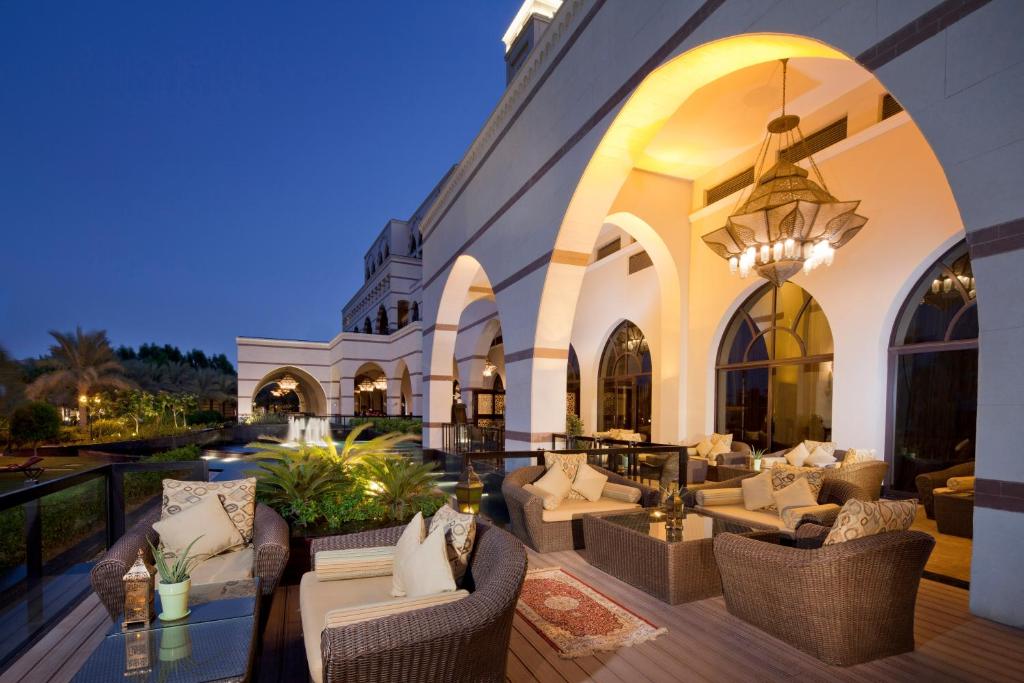 Eleganta terase ar rattan mēbelēm un iedegtiem laternām, kas nodrošina mierīgu atmosfēru. Fons veido arhitektūras elementi ar arku un izsmalcinātu apgaismojumu.