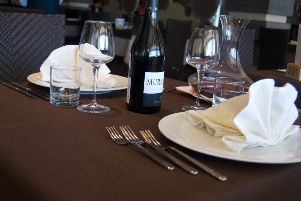 Elegantiesti klāts galda iestatījums ar vīna pudeli, glāzēm un salvetēm restorānā. Izsmalcināts dizains rada patīkamu atmosfēru maltītei.