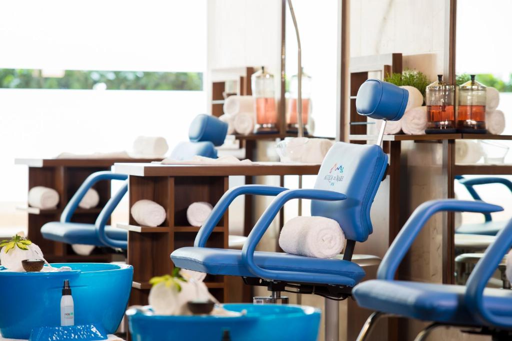 Mūsdienīgs spa salons ar zilu masāžas krēslu un relaksējošiem aksesuāriem. Telpa ir gaiša un ērta, radot mierīgu atmosfēru.