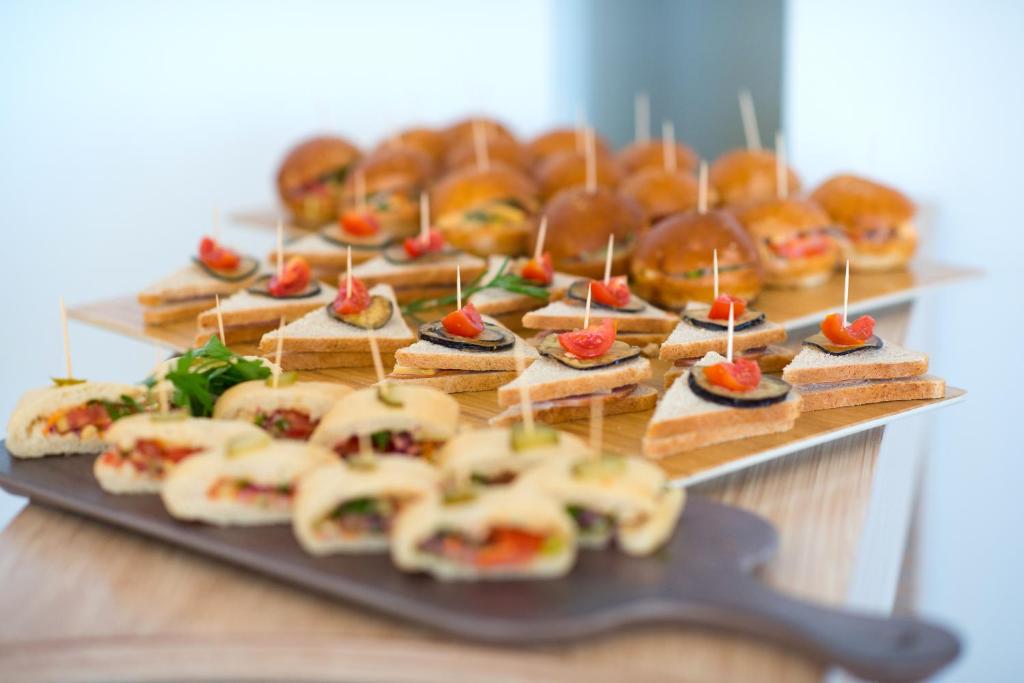 Uzkodu šķīvis ar dažādiem sendvičiem un burgeriem, dekorētiem ar tomātu gabaliņiem un koka zobu bakstāmiem. Ideāls risinājums pasākumiem un svinībām.