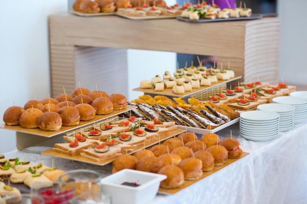 Daudzveidīgas uzkodas un mini maizītes uz galda svinīgā pasākumā, kas ietver saldumus un dārzeņu uzkodas.