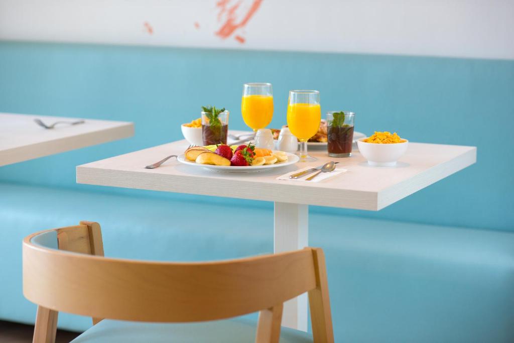 Broka veida galds ar sulīgām augļiem, apskārtām saldējuma un brokastu pārslām, papildināts ar oranžām sulām un kafiju. Interjers ar gaiši zilu akcentu.