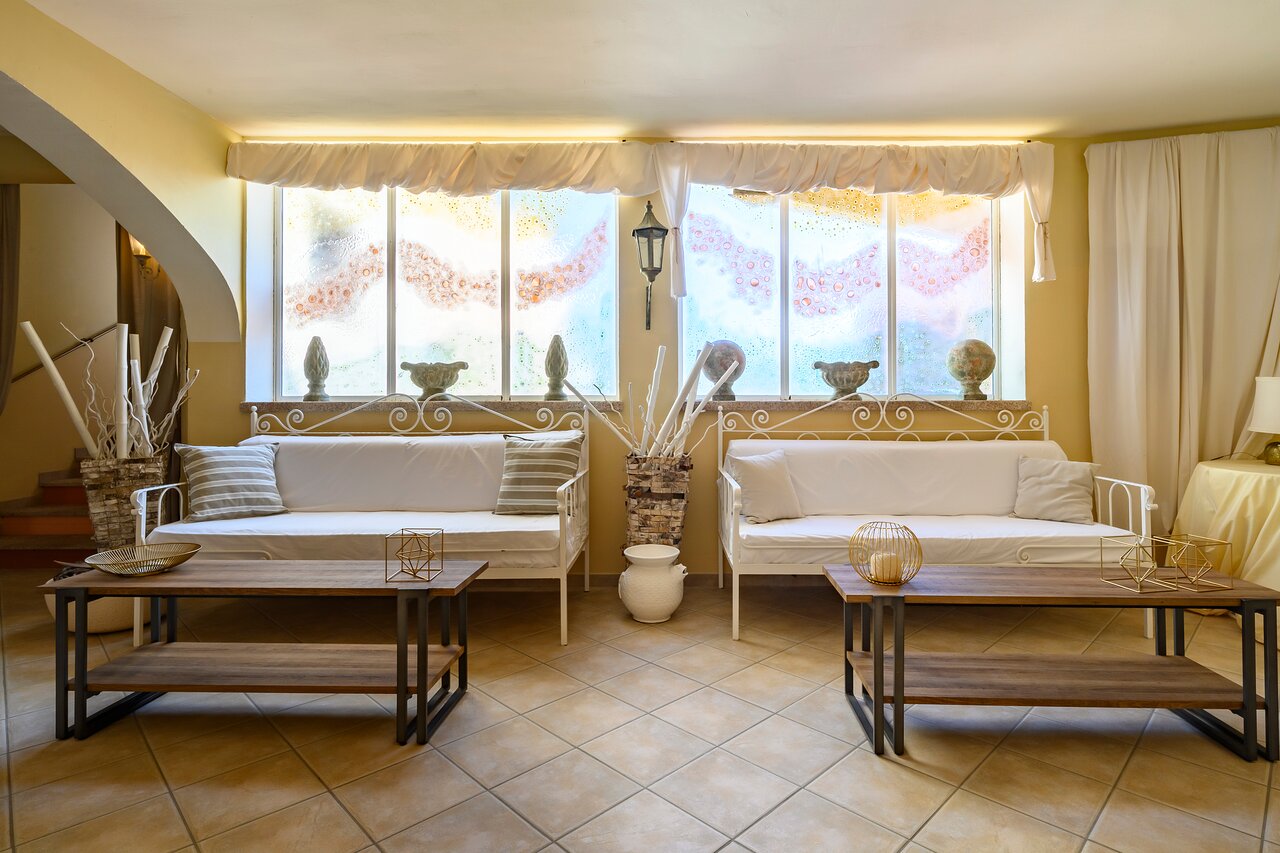 Elegants interjers Baia del Porto viesnīcā ar dīvāniem un dekorācijām.