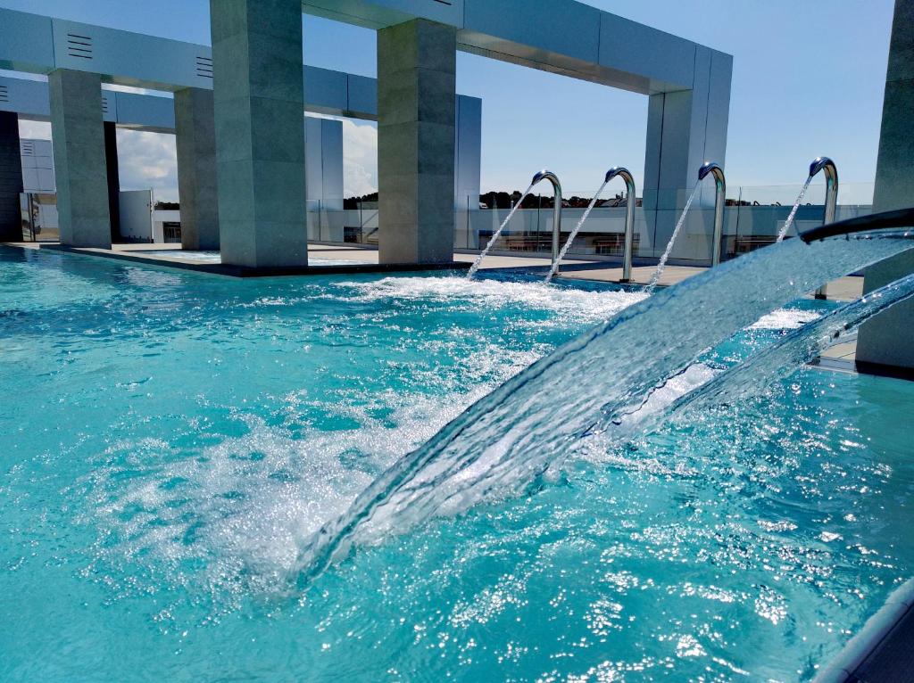 Mūsdienīgs peldbaseins ar strūklām un skaidru zilo ūdeni, ko ieskauj moderni arhitektūras elementi. Ideāla vieta atpūtai un relaksācijai.