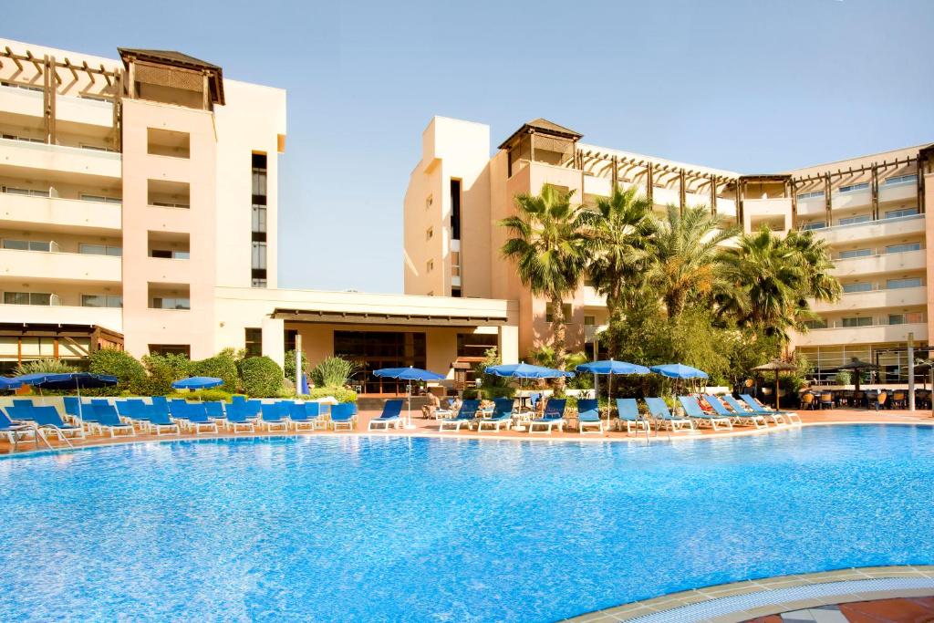 Luksusa viesnīcas komplekss ar plašu baseinu un saulessargiem, apkārt palmām un dārziem. Ideāli piemērots atpūtai un relaksācijai.