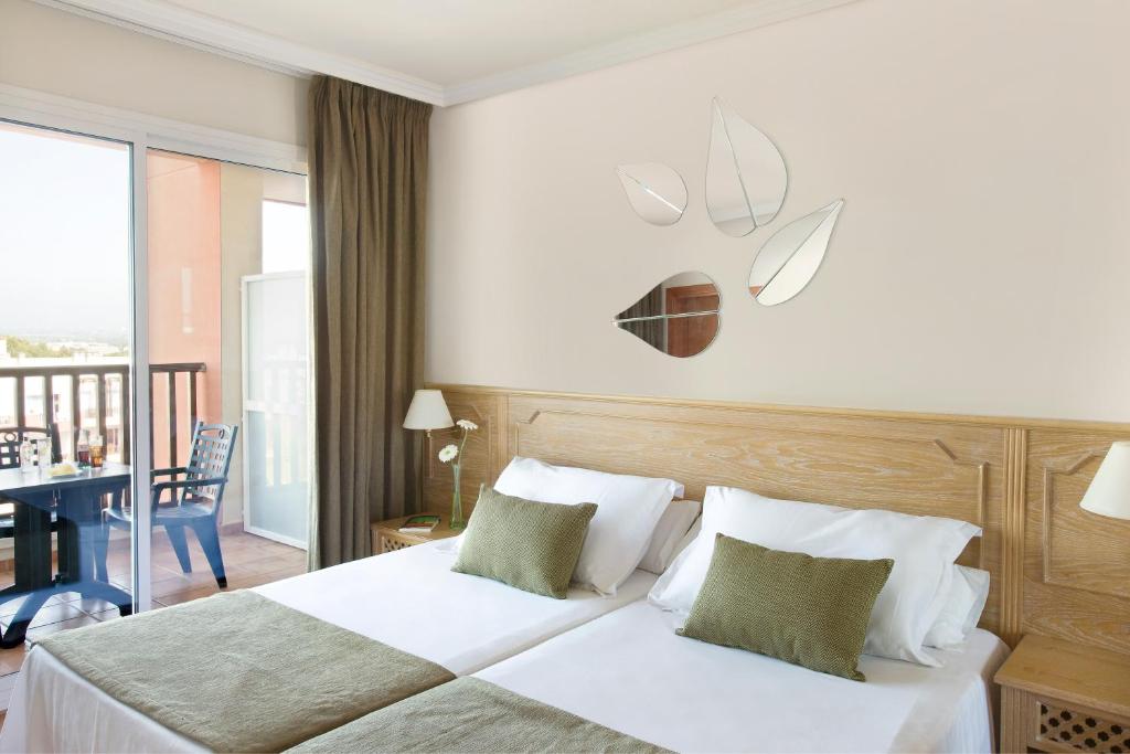 Mūsdienīga viesnīcas istaba ar divām gultām, dekorēta ar spoguļiem lapu formā un ar ērtiem spilveniem. Istabā ir balkons ar skatu uz ārpusi un neliela galda komplekts.