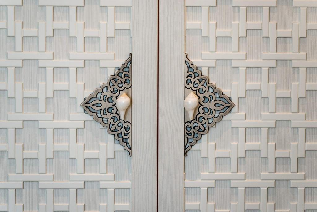 Dekoratīva durvju dizaina tuvplāns ar modernu ģeometrisko rakstu un izsmalcinātiem rokturiem, kas piešķir telpai eleganci.