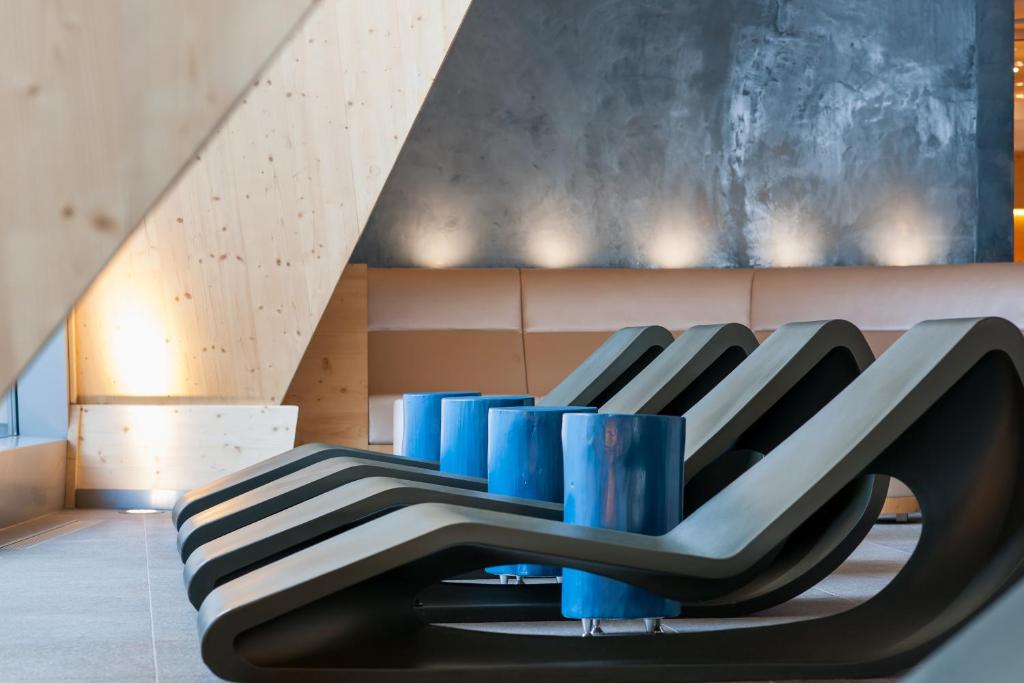 Mūsdienīga atpūtas zona ar stilizētiem melniem krēsliem un ziliem galdiņiem, kas radījuši relaksējošu atmosfēru. Interjers apvieno koka un betona elementus, radot estētisku harmoniju.