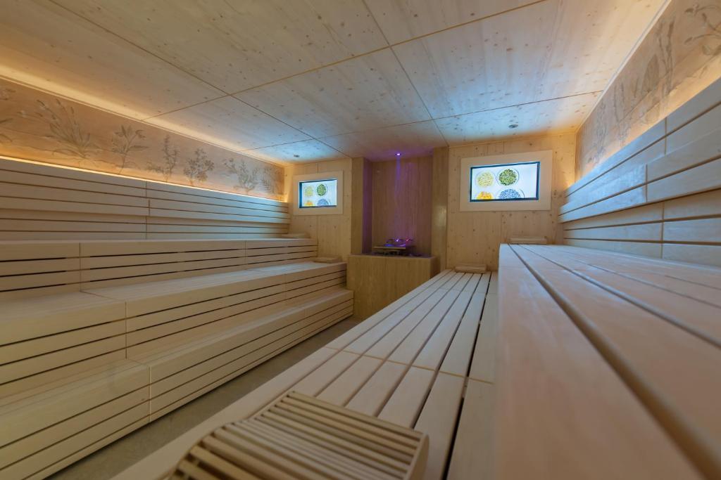 Mūsdienīga koka pirts ar ērtiem soliem un maigu apgaismojumu, radot relaksējošu atmosfēru. Logi ar dekoratīviem elementiem piešķir telpai unikālu šarmu.