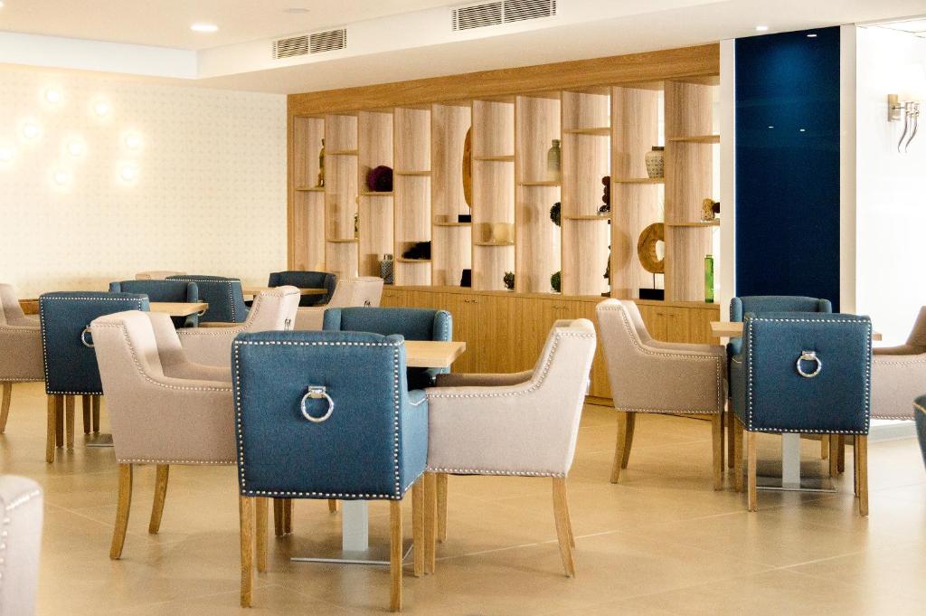 Mūsdienīgs interjers ar elegantiem krēsliem un koka plauktiem, kas izceļ dekoratīvus elementus. Ideāla vieta relaksācijai un socializācijai.