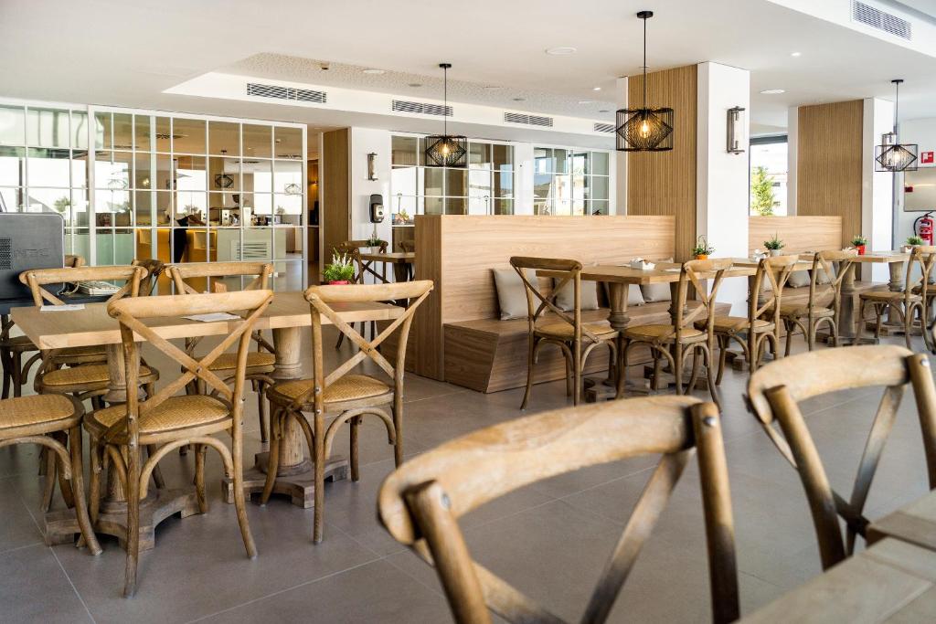 Moderns restorāna interjers ar koka galdiem un krēsliem, kas izceļ gaisīgu un siltu atmosfēru. Telpā ir lieli logi, kas nodrošina dabīgu apgaismojumu.