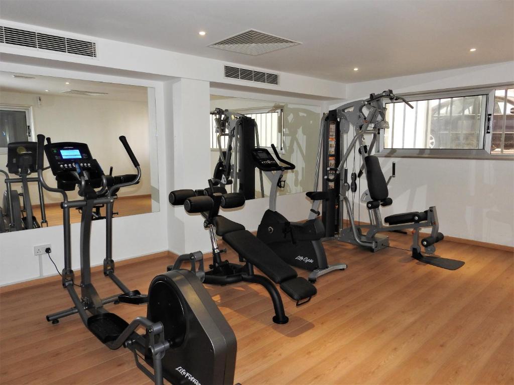 Mūsdienīga sporta zāle ar dažādām trenažieru iekārtām un spoguļiem, kas nodrošina komfortablu treniņu vidi. Gaismas un koka grīdas papildina telpas estētiku.