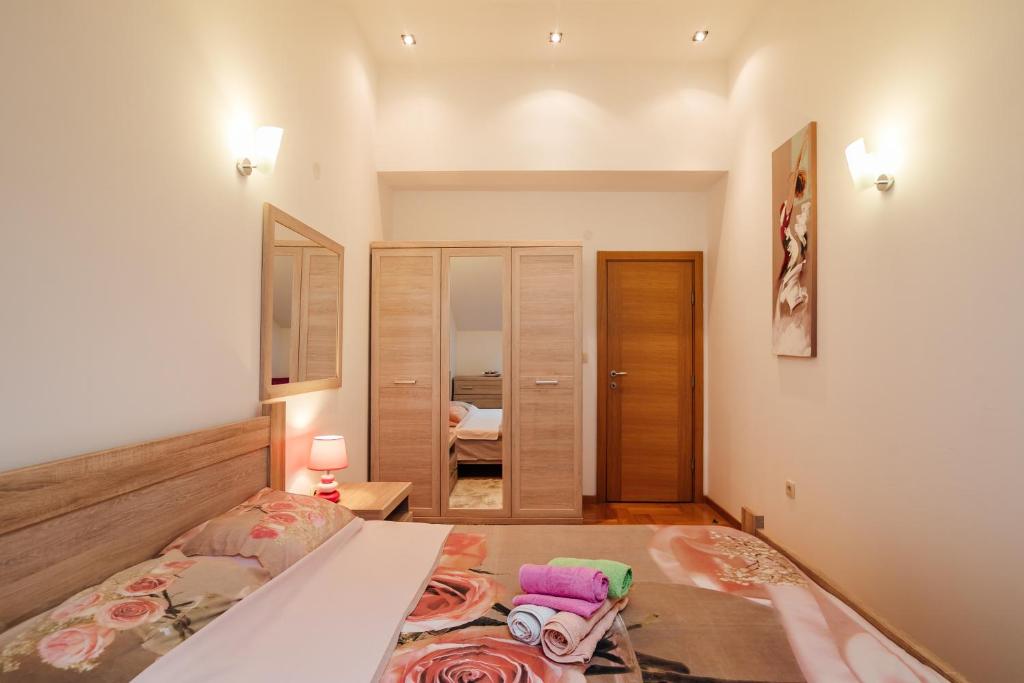 Mūsdienīga guļamistaba ar gultu, dekorētu ar rozēm, un atspoguļojumu spogulī. Sienās ir gaismas un koka skapji, radot siltu un mājīgu atmosfēru.