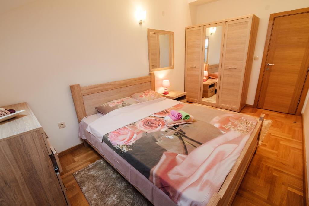 Gaiša guļamistaba ar koka mēbelēm, ēršu gultu un rožu motīvu gultas veļu. Telpā ir skapji un naktslampiņas, radot mājīgu atmosfēru.