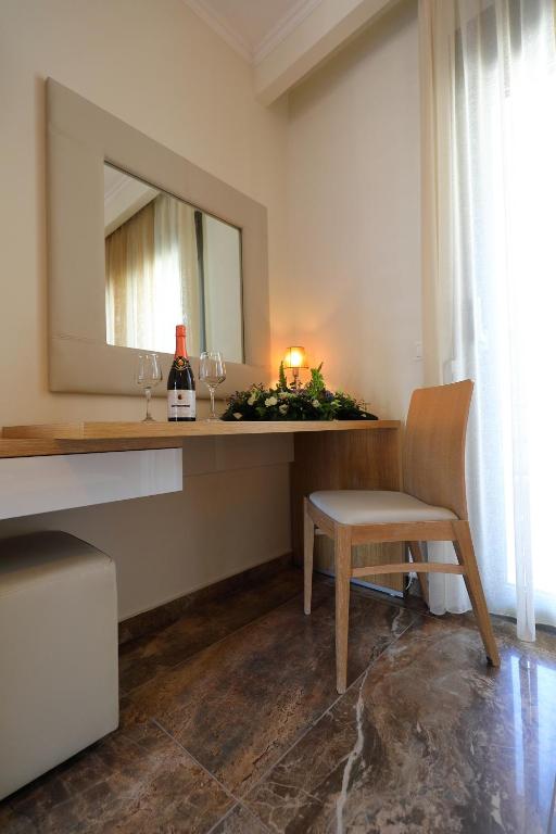 Mūsdienīgs interjers ar elegantu galdu, krēslu un spoguli, kurā redzams šampanietis un glāzes, radot romantisku atmosfēru. Gaismas un dabiskā apgaismojuma harmonija papildina telpas estētiku.