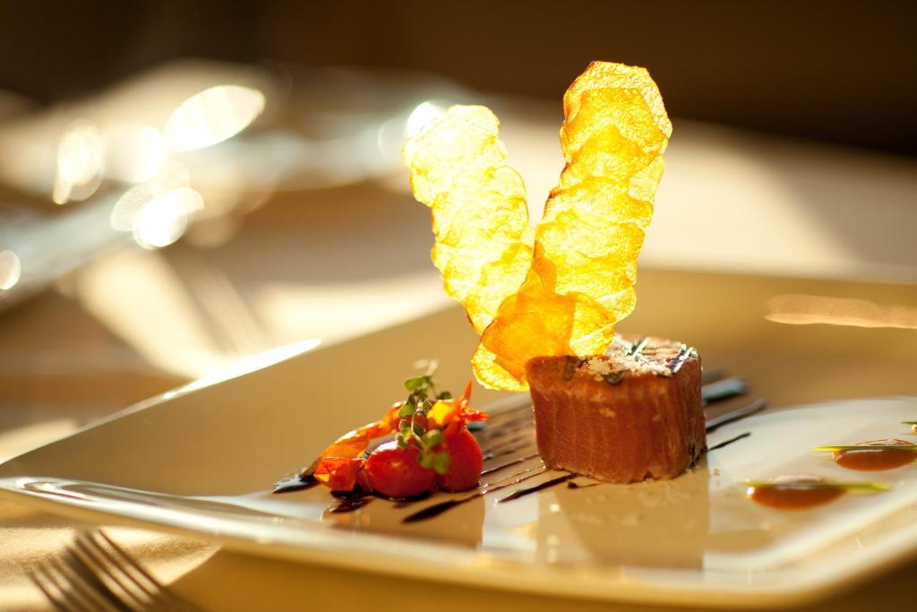 Gurķu salāti ar krēmīgu mērci un kraukšķīgu kartupeļu čipsu dekorāciju, pasniegti eleganta dizaina šķīvī.