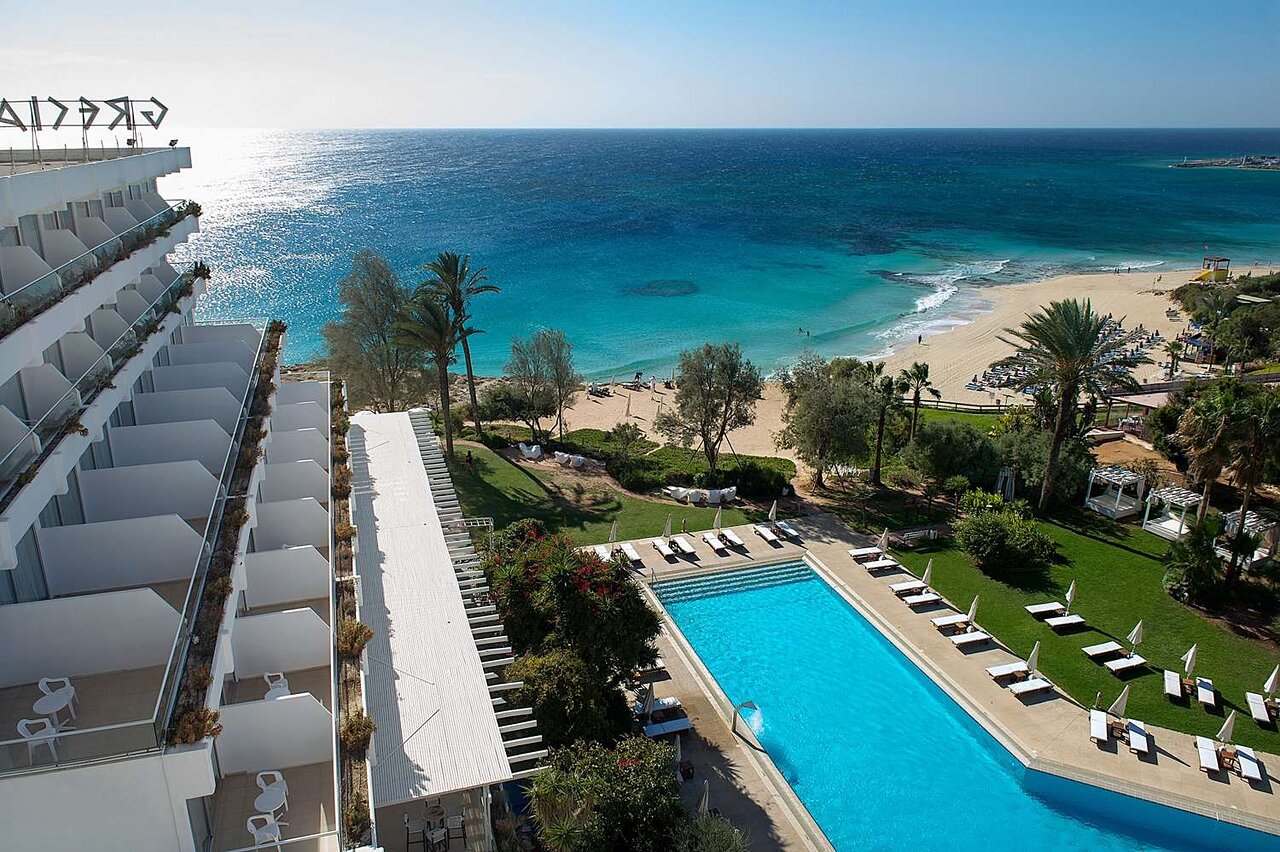 Viesnīcas komplekss ar baseinu, blakus pludmalei un zilo ūdeņu ainava, kas aicina uz relaksāciju un atpūtu. Ideāla vieta brīvdienām. panoramic view with beach and pools
