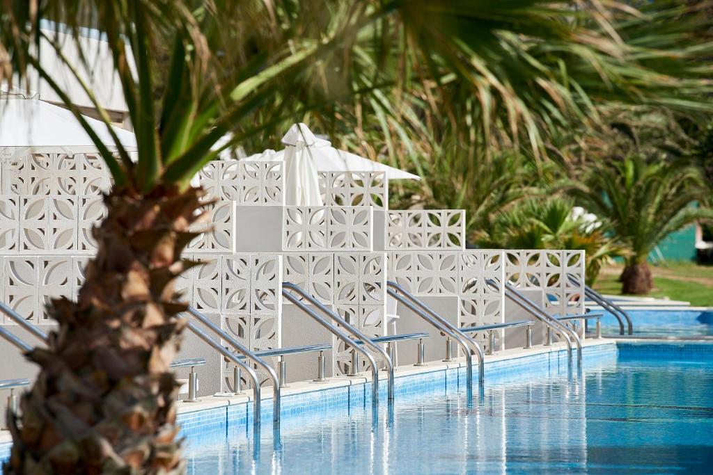 Baseins ar modernu dizainu, apkārt palmām un sauļošanās krēsliem, radot atpūtas atmosfēru. Ideāli piemērots relaksācijai un vasaras izklaidēm.