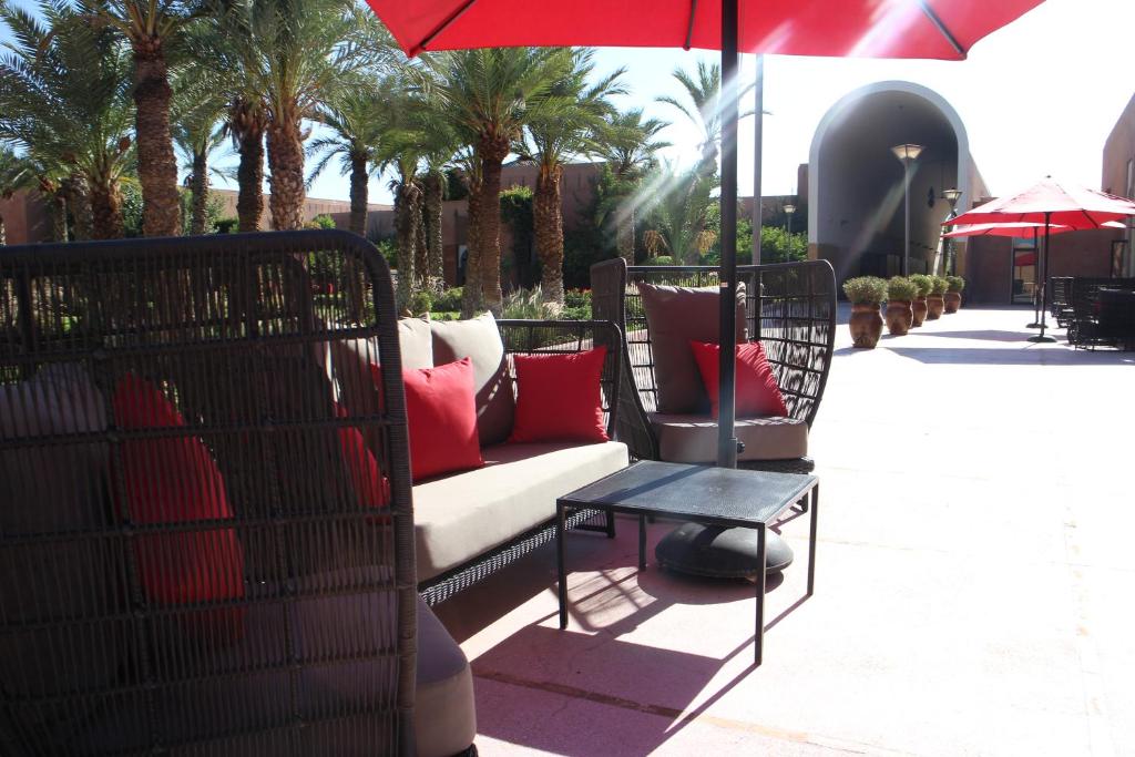 Skaista āra atpūtas zona ar ērtām mēbelēm un sarkaniem saules jumtiem, ko ieskauj palmas. Ideāla vieta relaksācijai un baudīšanai.