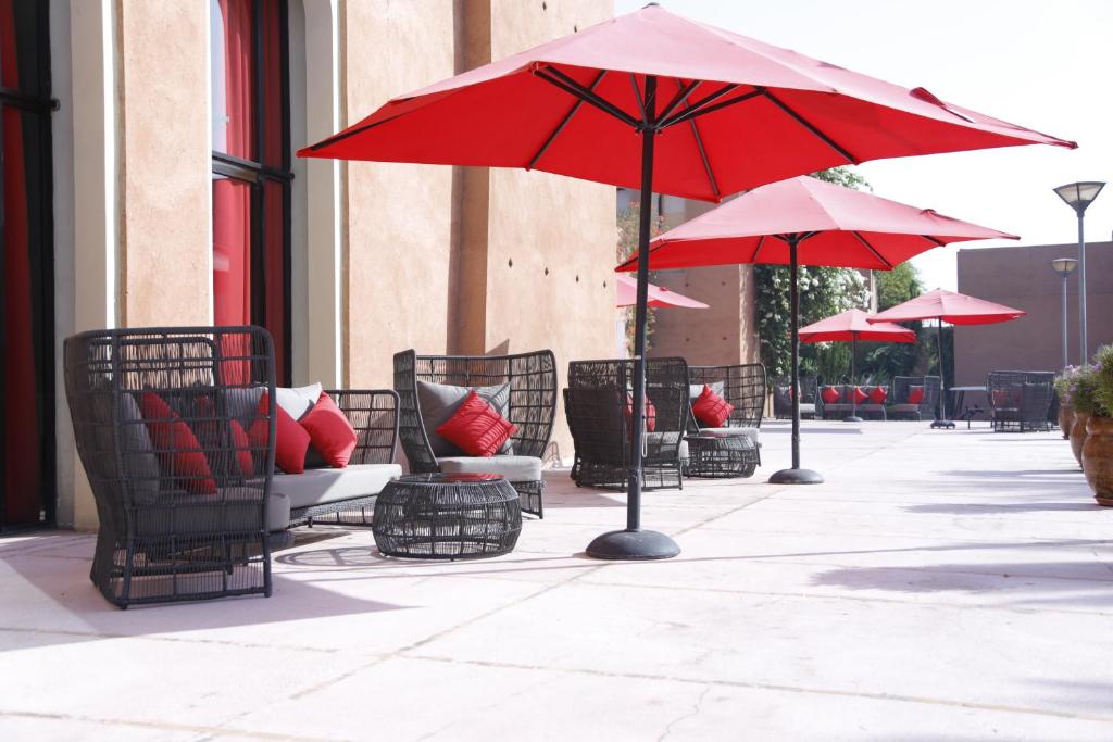 Āra terase ar komfortablām mēbelēm, sarkaniem lietussargiem un spilveniem, kas nodrošina ērtu atpūtu saulainā vidē. Ideāla vieta relaksācijai un sociālai sanākšanai.