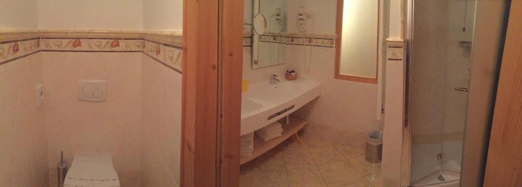 Mūsdienīga vannas istaba ar dušu, tualeti un izsmalcinātu apgaismojumu. Telpa ir iekārtota ar koka elementiem un elegantiem dekoriem.