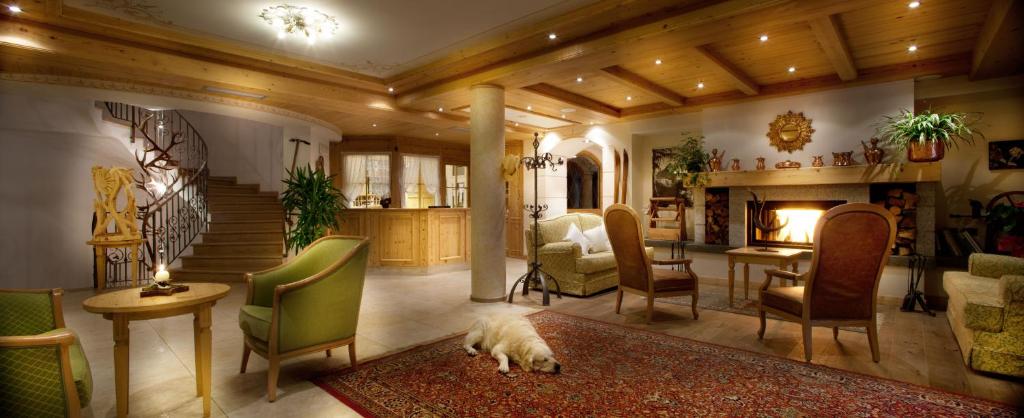 Mūsdienīga viesnīcas viesistaba ar koka detaļām, siltu apgaismojumu un ērtām mēbelēm. Uz grīdas atrodas paklājs, bet stūrī guļ suns.