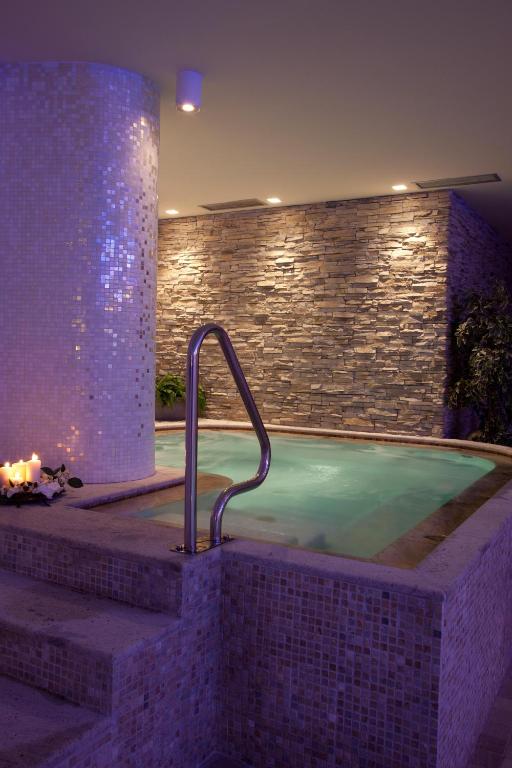 Mūsdienīgs spa ar relaksējošu ūdens baseinu, akmens sienām un mīkstu apgaismojumu, radot mierīgu atmosfēru.