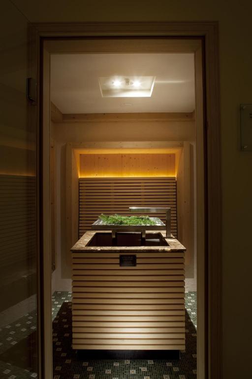 Mūsdienīga sauna ar koka apdari un apgaismojumu, radot relaksējošu atmosfēru. Centrā atrodas dabiska zaļumu kompozīcija.