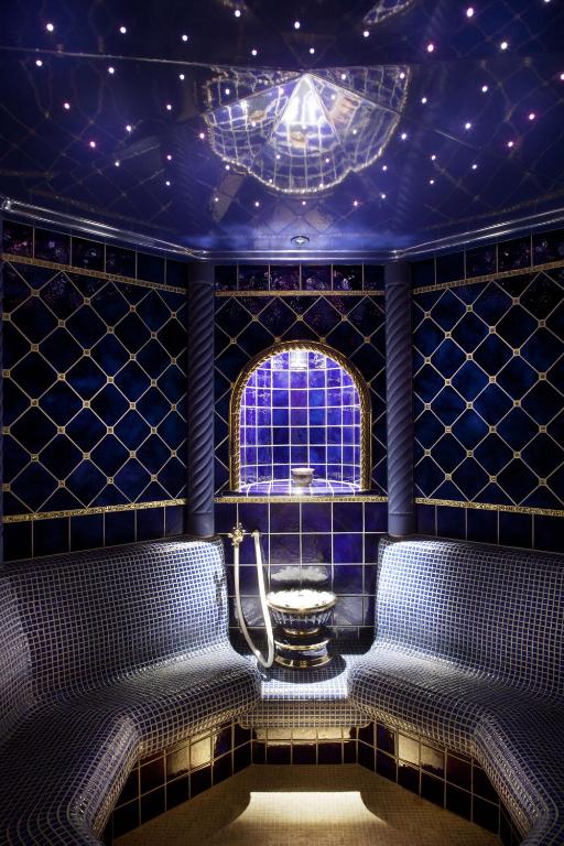 Elegants tvaika pirts interjers ar tumši zilu flīzējo un zvaigžņu apgaismojumu. Telpa ir iekārtota ar mīkstiem sēdekļiem un dekoratīvu akcentu centrā.