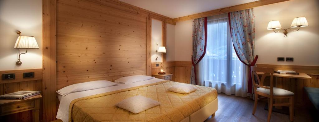 Mūsdienīga viesnīcas numuriņa interjers ar koka apdari, divguļamā gulta un dabiska apgaismojuma avoti. Logi ar aizkariem un koka mēbeles rada mājīgu atmosfēru.