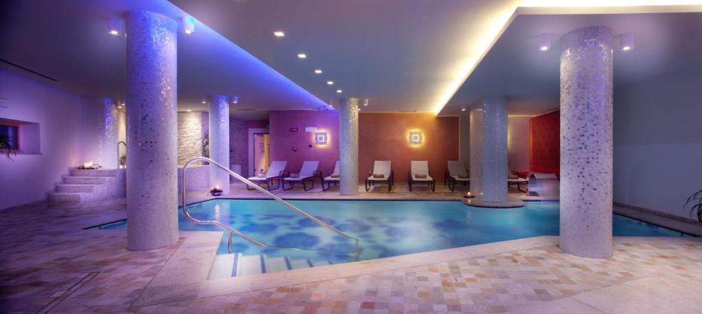 Mūsdienīgs spa ar iekštelpu baseinu, apgaismotu ar maigu gaismu un relaksējošām atpūtas zonām. Telpa ir rotāta ar kolonnām un elegantu interjeru, radot mierīgu atmosfēru.