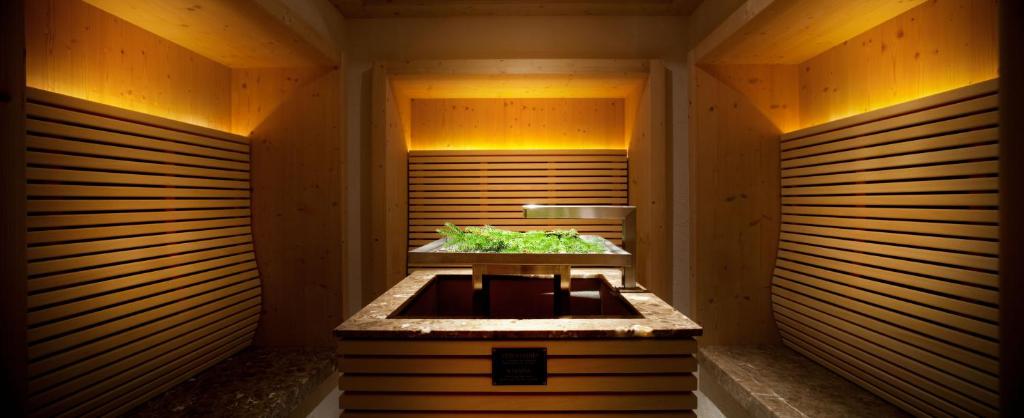 Mūsdienīga koka interjera telpa ar apgaismojumu un augiem centrā, radot relaksējošu atmosfēru. Ideāla vieta atpūtai un labsajūtai.