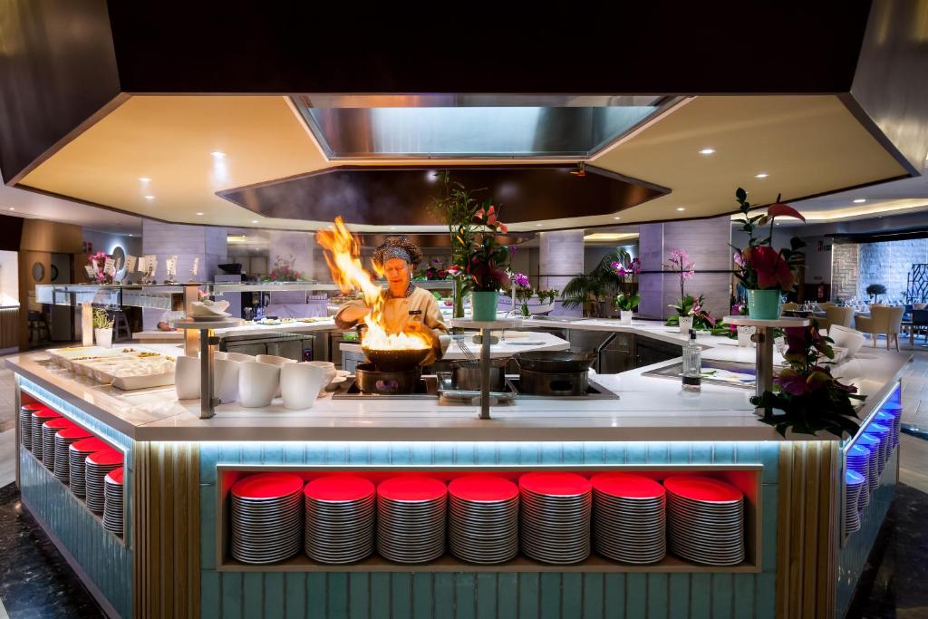 Kvalitatīvs restorāns ar šefpavāru, kurš gatavo ēdienus ar uguni, piedāvājot dinamisku kulinārijas pieredzi. Moderns interjers, ko papildina ziedi un eleganta apgaismojums.