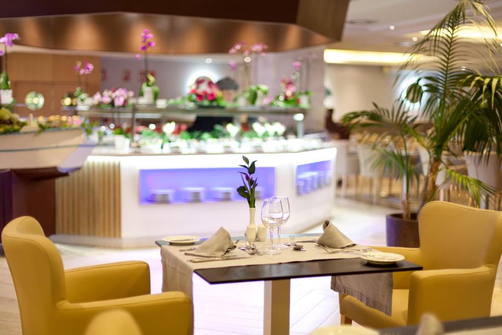 Elegants restorāns ar ziedu dekorācijām un gaumīgu galda klājumu, piedāvājot plašu ēdienu izvēli. Gaisotne ir mierīga un aicinoša, ideāla romantiskām vakariņām.